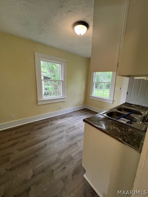 kitchen featuring dark stone countertops, a textured ceiling, sink, and dark hardwood / wood-style flooring