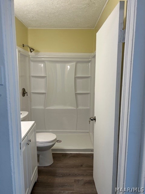 bathroom with a shower, vanity, hardwood / wood-style flooring, toilet, and a textured ceiling