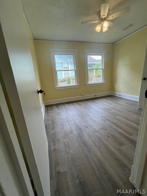 spare room featuring dark hardwood / wood-style floors, ceiling fan, and crown molding