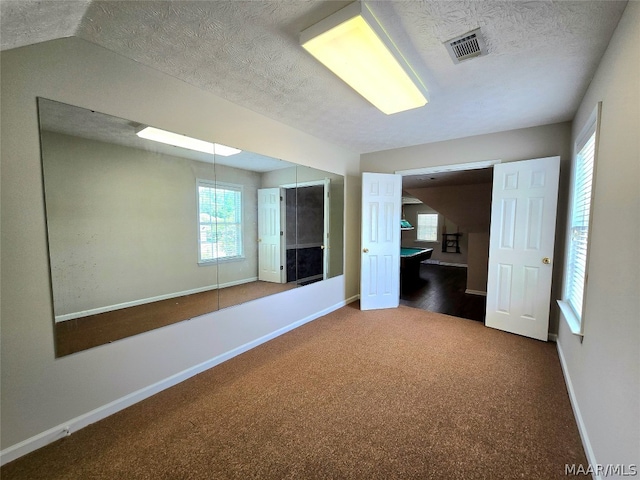 carpeted empty room with lofted ceiling and a textured ceiling