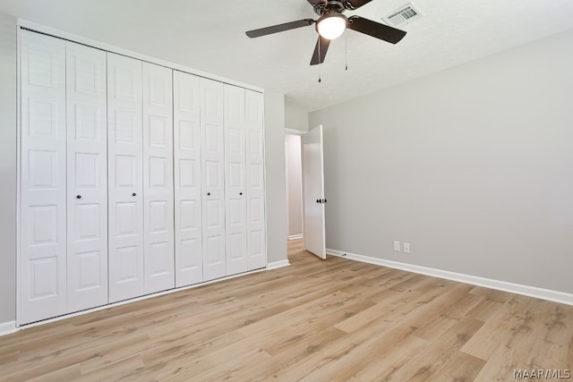 unfurnished bedroom featuring ceiling fan, light hardwood / wood-style flooring, and a closet