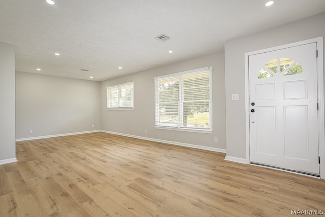 foyer with a textured ceiling, light wood-type flooring, and plenty of natural light