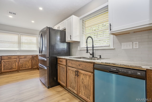 kitchen featuring appliances with stainless steel finishes, sink, backsplash, light wood-type flooring, and white cabinetry