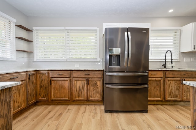 kitchen featuring a wealth of natural light, decorative backsplash, light hardwood / wood-style floors, and stainless steel refrigerator with ice dispenser