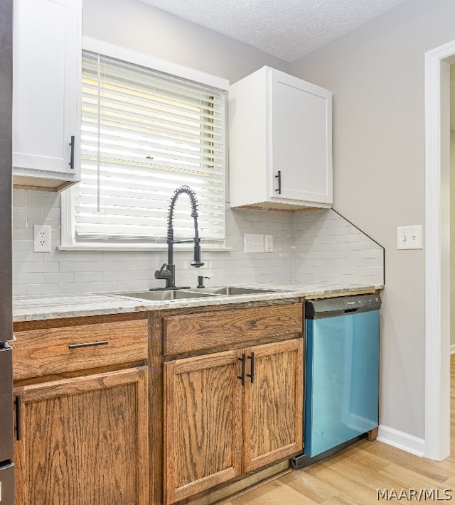 kitchen with tasteful backsplash, stainless steel dishwasher, light wood-type flooring, a textured ceiling, and white cabinetry