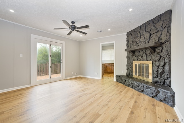 living room featuring light hardwood / wood-style flooring, a fireplace, a textured ceiling, ceiling fan, and ornamental molding