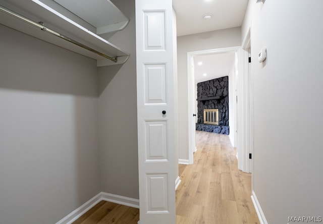 walk in closet featuring a fireplace and light wood-type flooring