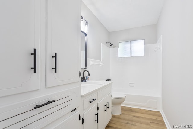 full bathroom with vanity, washtub / shower combination, wood-type flooring, and toilet