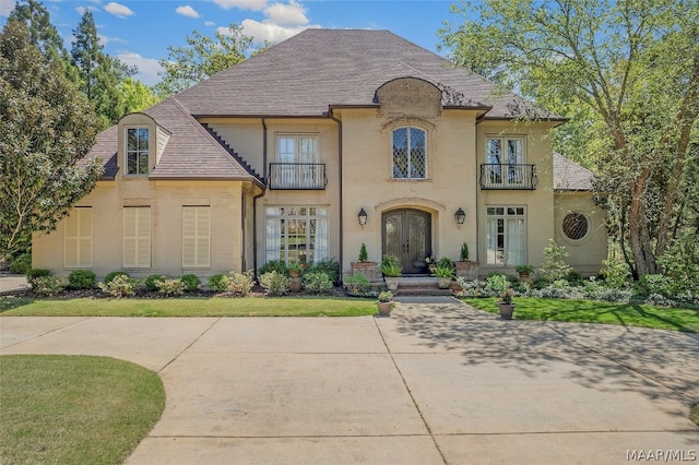 french country style house with a front yard and a balcony