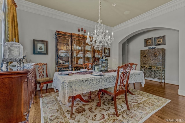 dining area featuring hardwood / wood-style floors, crown molding, and an inviting chandelier