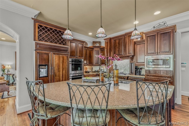 kitchen featuring light hardwood / wood-style flooring, a breakfast bar, and built in appliances