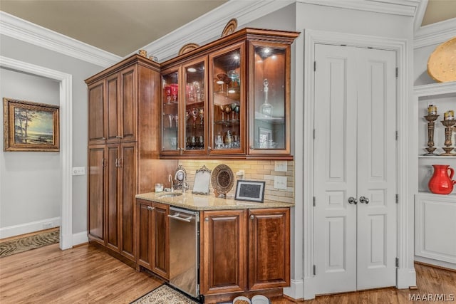 bar featuring light hardwood / wood-style flooring, tasteful backsplash, light stone countertops, and ornamental molding