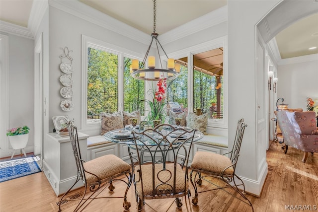 dining room featuring a wealth of natural light, crown molding, a notable chandelier, and light wood-type flooring