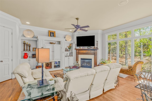 living room with light hardwood / wood-style flooring, crown molding, ceiling fan, and a wealth of natural light