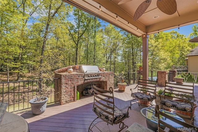 wooden deck with an outdoor kitchen, ceiling fan, and grilling area