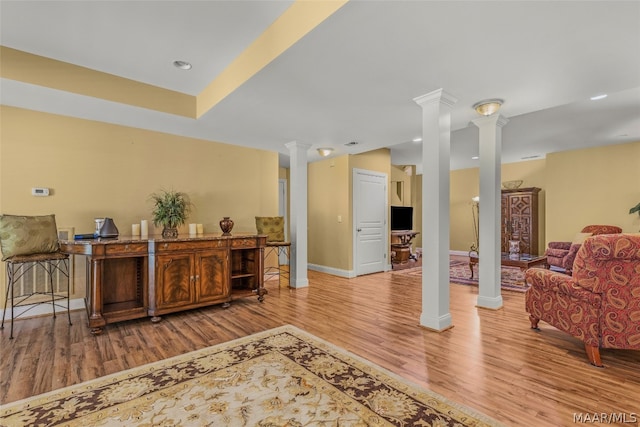 interior space featuring decorative columns and light wood-type flooring