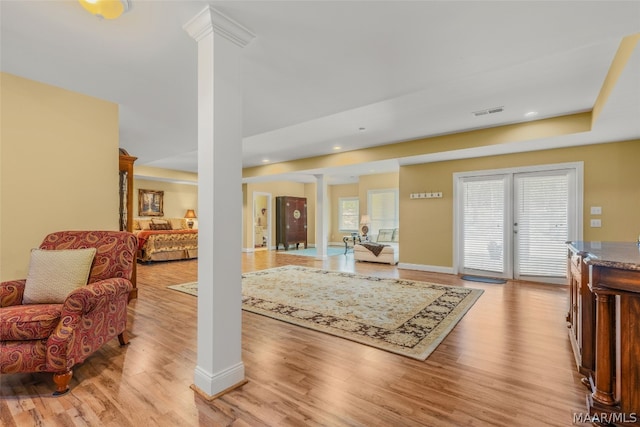 interior space featuring french doors, decorative columns, and light wood-type flooring