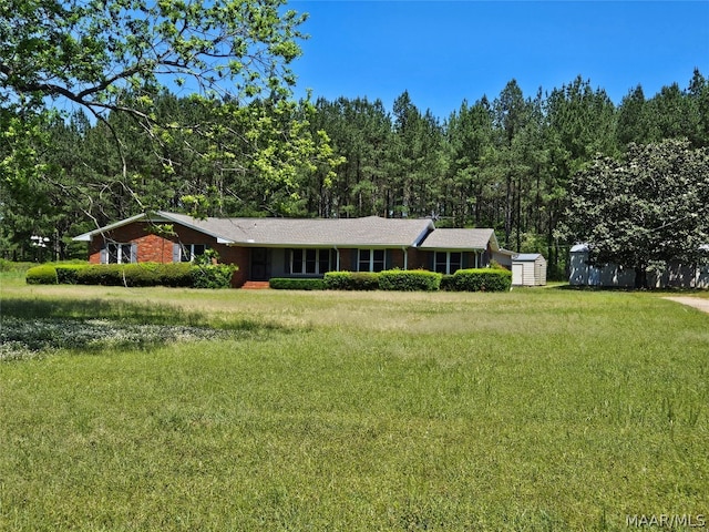 ranch-style house featuring a front yard and a shed