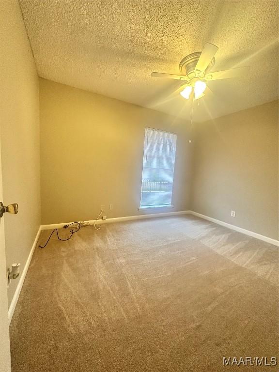 carpeted spare room with ceiling fan and a textured ceiling