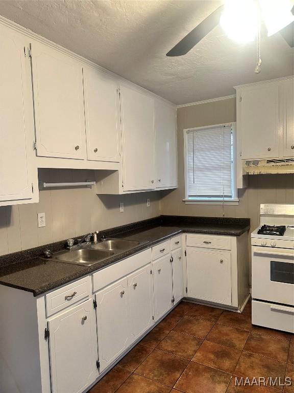 kitchen featuring sink, white gas range oven, ceiling fan, a textured ceiling, and white cabinetry