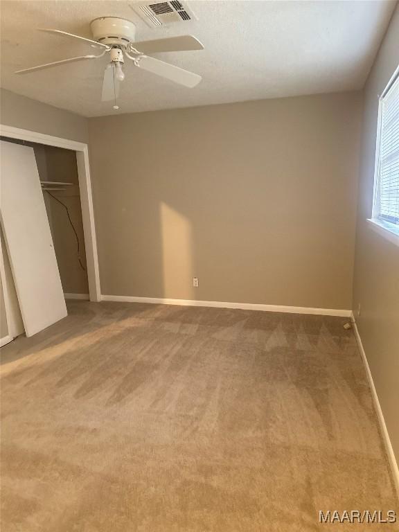 unfurnished bedroom with ceiling fan, a closet, and carpet