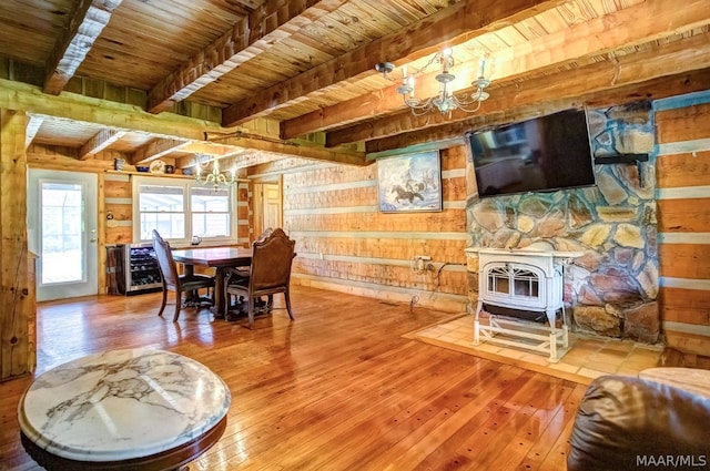 dining room with wooden ceiling, wooden walls, beamed ceiling, a notable chandelier, and wood-type flooring