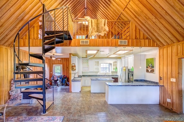 kitchen with a wealth of natural light, wooden walls, white cabinets, and decorative light fixtures