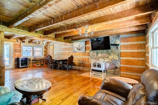 living room with a wood stove, a wealth of natural light, beverage cooler, and wood walls