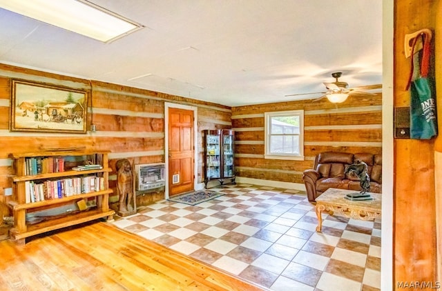 sitting room with heating unit, wooden walls, and ceiling fan