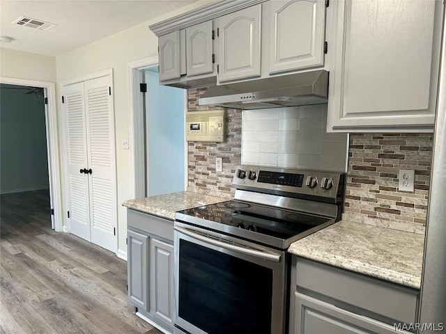 kitchen with tasteful backsplash, gray cabinetry, stainless steel electric range, and light wood-type flooring