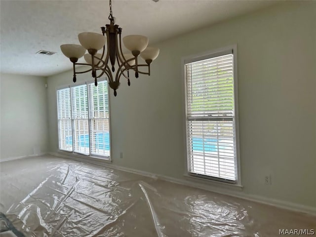 unfurnished room with a chandelier and a healthy amount of sunlight