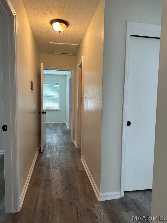 hall featuring a textured ceiling and dark wood-type flooring