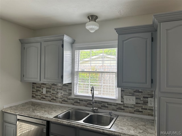 kitchen with tasteful backsplash, gray cabinets, sink, and stainless steel dishwasher