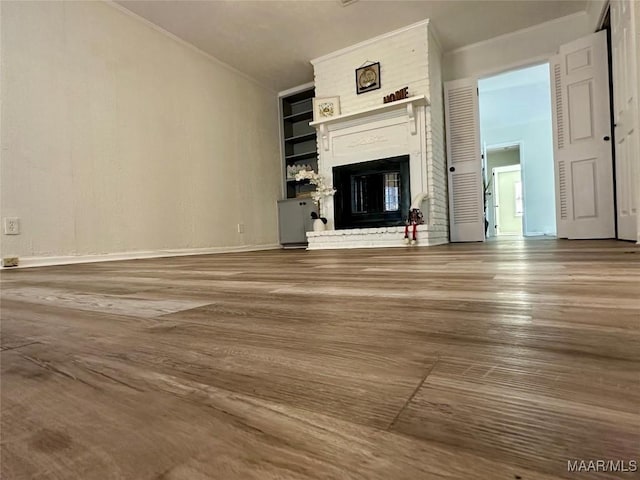 unfurnished living room featuring hardwood / wood-style flooring and a brick fireplace