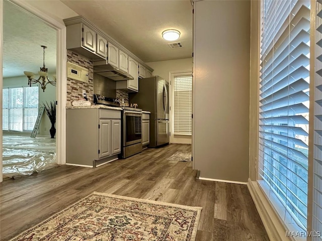 kitchen with an inviting chandelier, decorative backsplash, a textured ceiling, appliances with stainless steel finishes, and dark hardwood / wood-style flooring