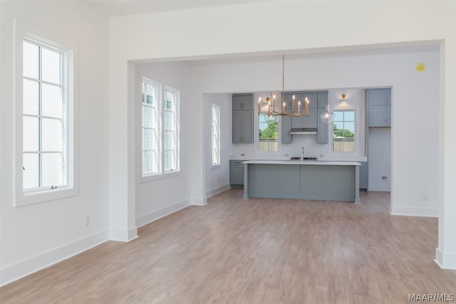 kitchen featuring a wealth of natural light, an inviting chandelier, pendant lighting, and light wood-type flooring