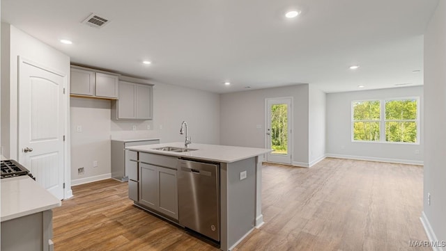 kitchen featuring a kitchen island with sink, gray cabinets, dishwasher, and sink