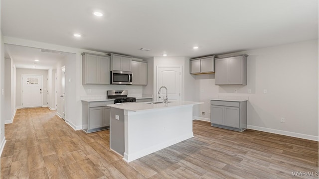 kitchen featuring a kitchen island with sink, sink, gray cabinets, and appliances with stainless steel finishes