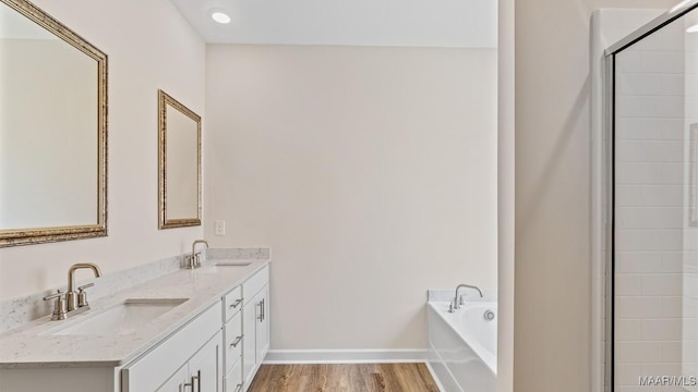 6601 Firefly Ln, Montgomery, AL 36116 - bathroom with wood finished floors, a bath, double vanity, a shower with door, and baseboards