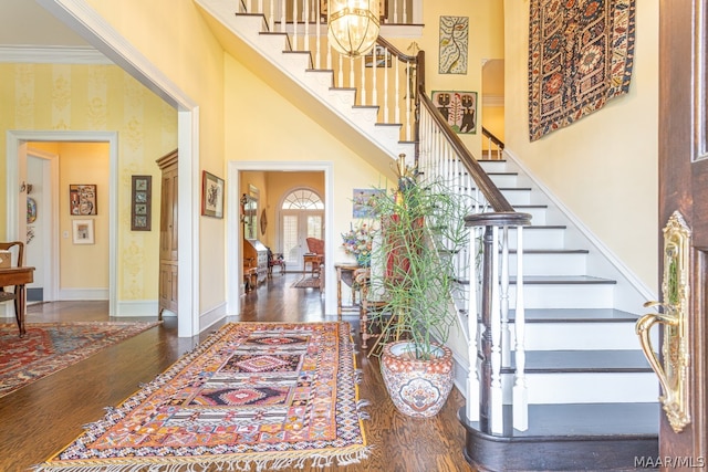 staircase featuring crown molding, dark wood-type flooring, and a towering ceiling