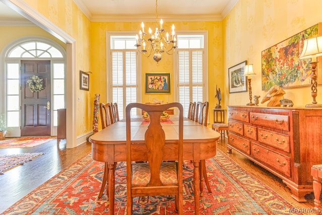 dining area with hardwood / wood-style floors, ornamental molding, and a chandelier