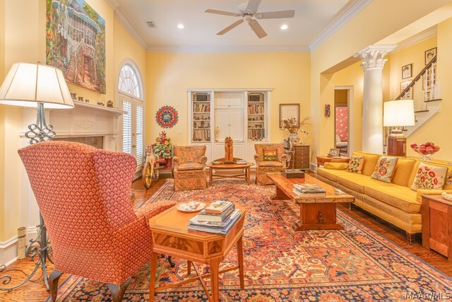 living room featuring crown molding, wood-type flooring, ornate columns, and ceiling fan