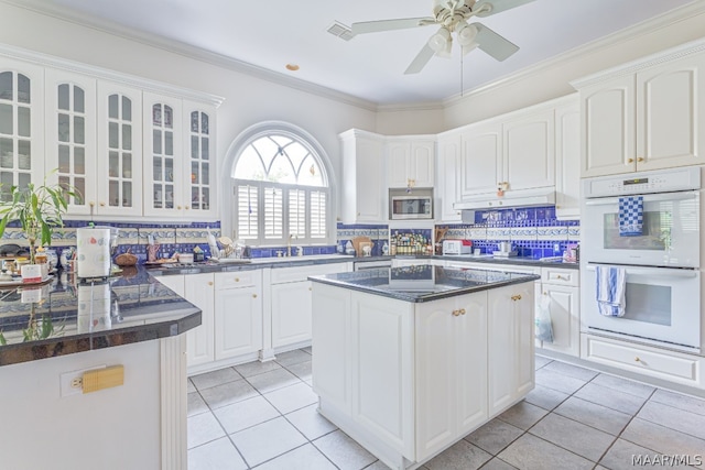 kitchen featuring crown molding, double oven, backsplash, stainless steel microwave, and ceiling fan