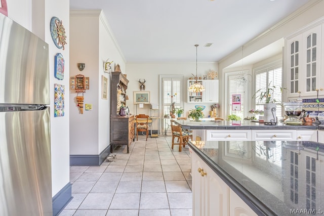 kitchen featuring hanging light fixtures, white cabinetry, a healthy amount of sunlight, and stainless steel refrigerator