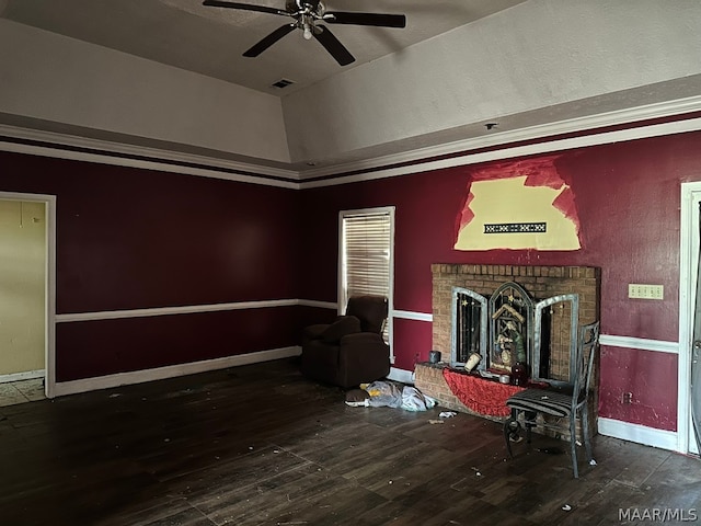 interior space with ceiling fan, a tray ceiling, hardwood / wood-style flooring, and a brick fireplace