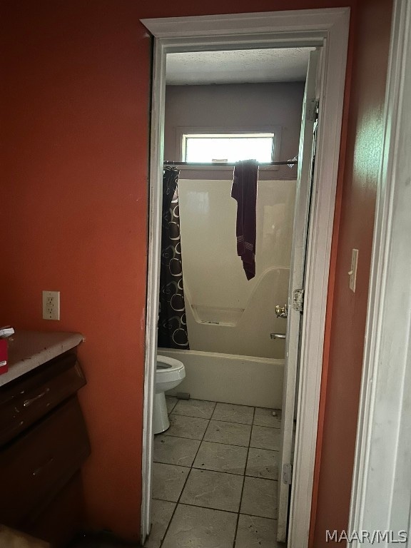 bathroom with tile flooring, shower / bath combo, and toilet