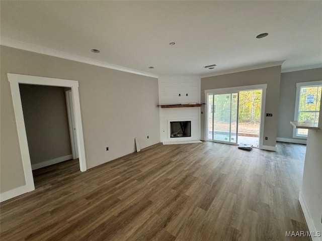 unfurnished living room with ornamental molding, wood-type flooring, and a large fireplace