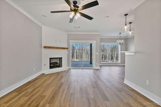 unfurnished living room with crown molding, a large fireplace, ceiling fan with notable chandelier, and light hardwood / wood-style floors