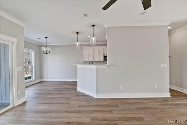 unfurnished living room featuring crown molding, ceiling fan with notable chandelier, and light hardwood / wood-style floors