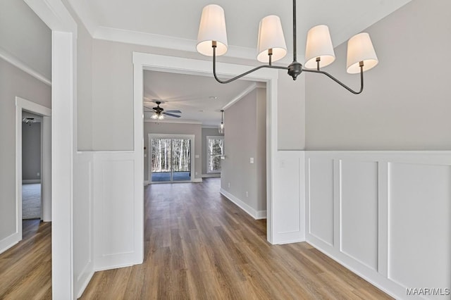 unfurnished dining area with hardwood / wood-style floors, crown molding, and ceiling fan